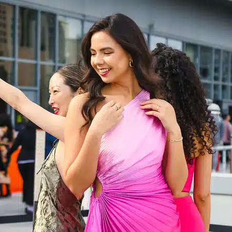 Group of women in elegant dresses enjoying a vibrant event, showcasing stylish attire and joyful expressions, reflecting a premium photo experience.