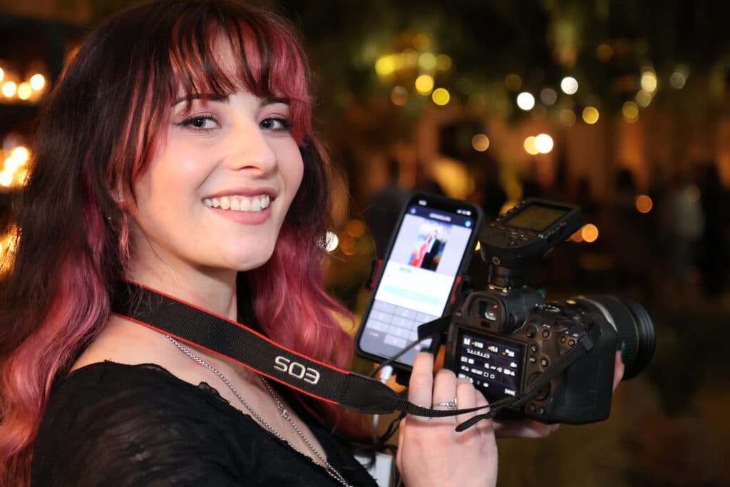 Woman smiling holding a camera and a phone