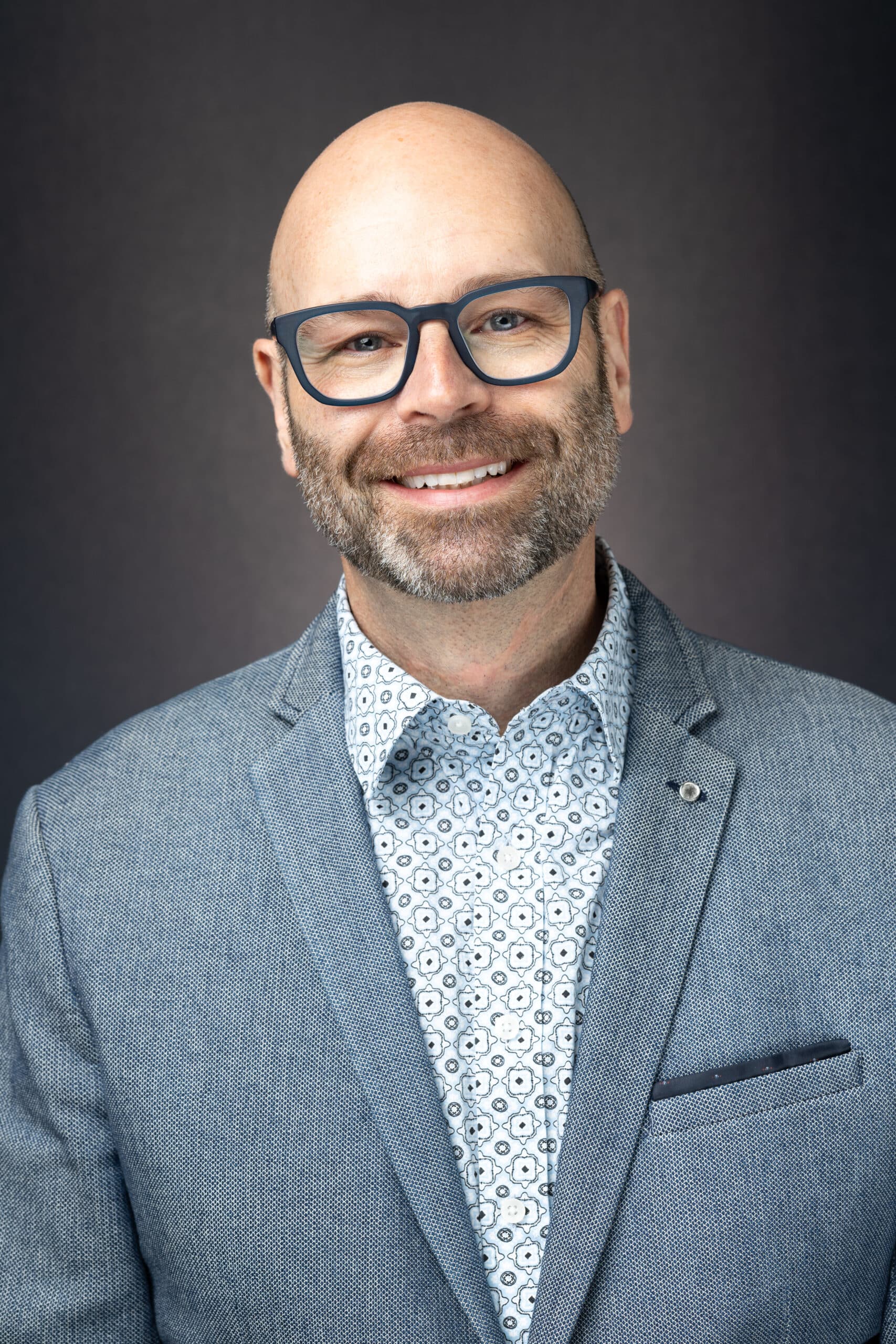 Professional headshot portrait of a man with glasses, showcasing Pop Life Photo's on-site photography services.