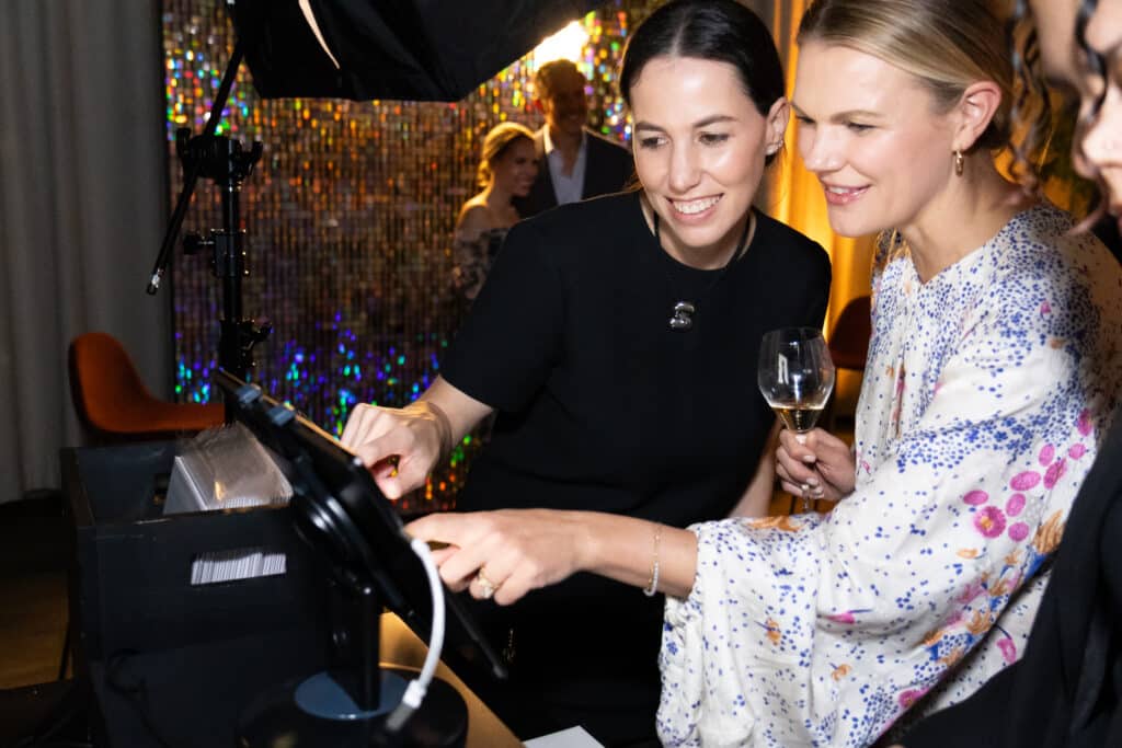 Two women interacting with a photo booth setup