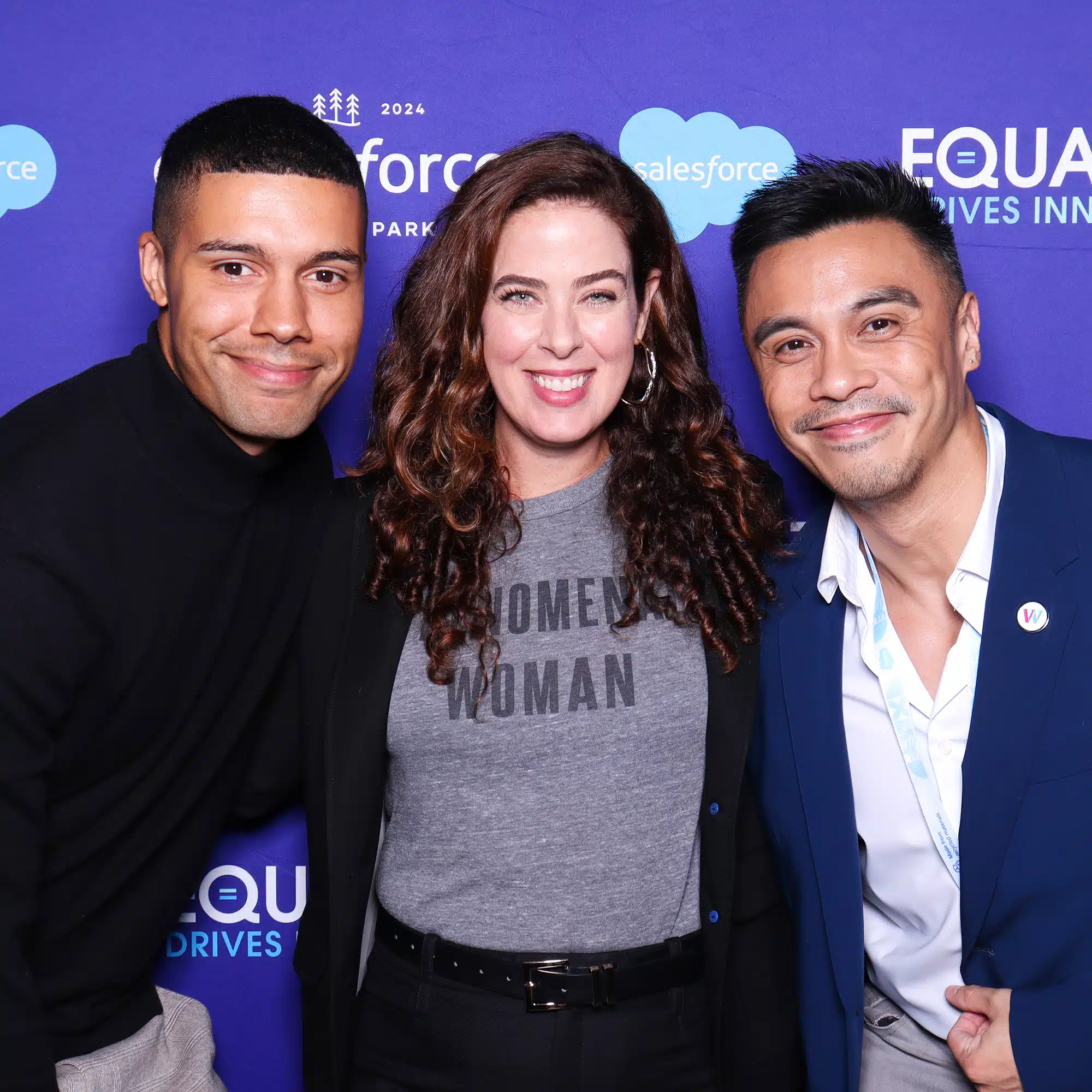 Group of three individuals posing together in front of a branded backdrop featuring Salesforce and Equality messaging, showcasing a corporate photo booth experience.