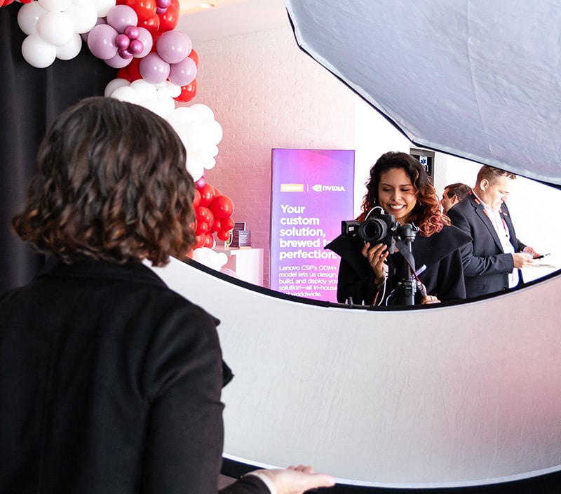 Woman smiling and holding a camera, capturing a guest in a professional photography setup with balloons in the background, reflecting the high-end event experience offered by Pop Life Photo.