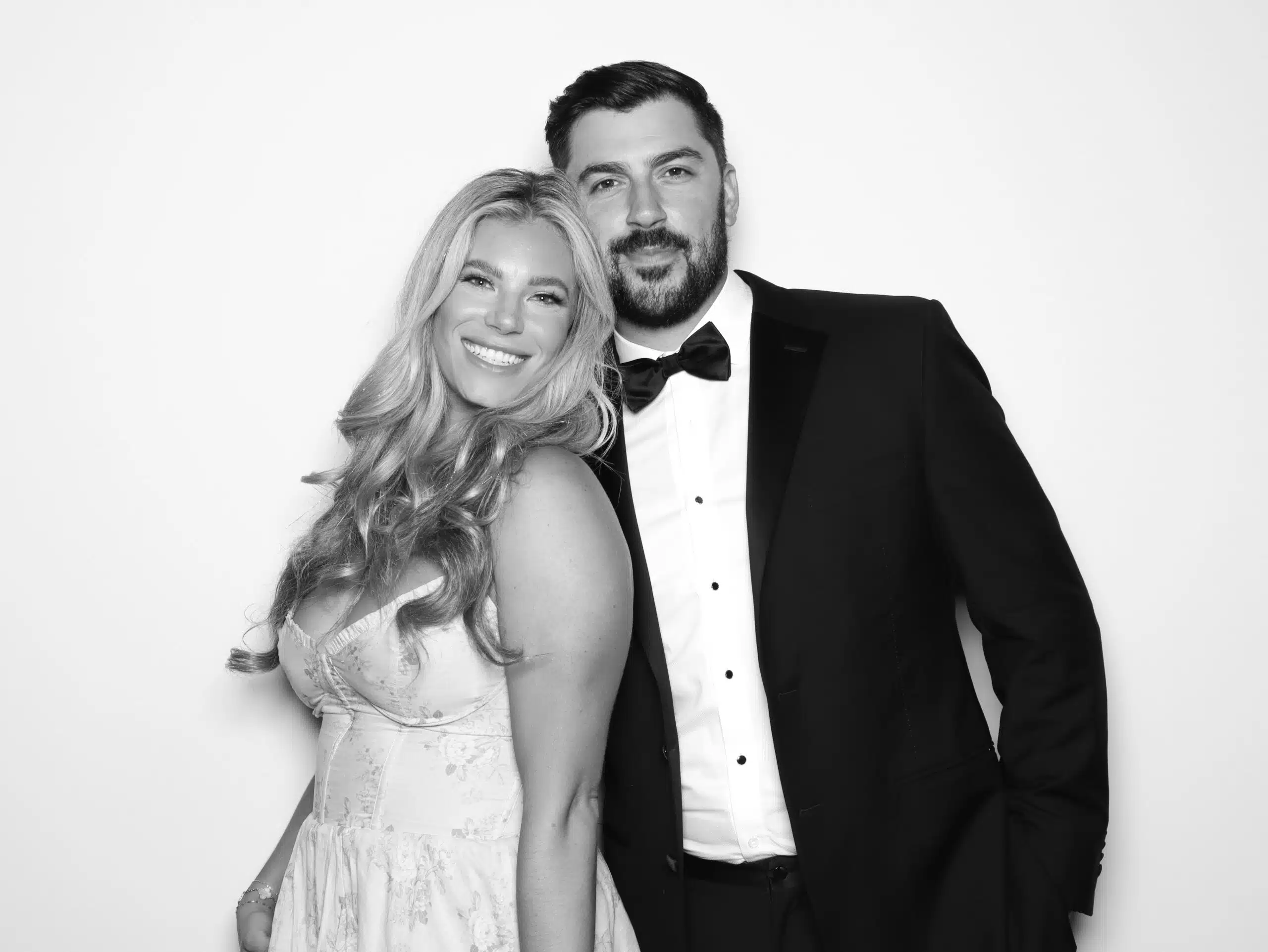 Couple posing in elegant attire for a Glam Photo Booth portrait, showcasing timeless black-and-white photography style.