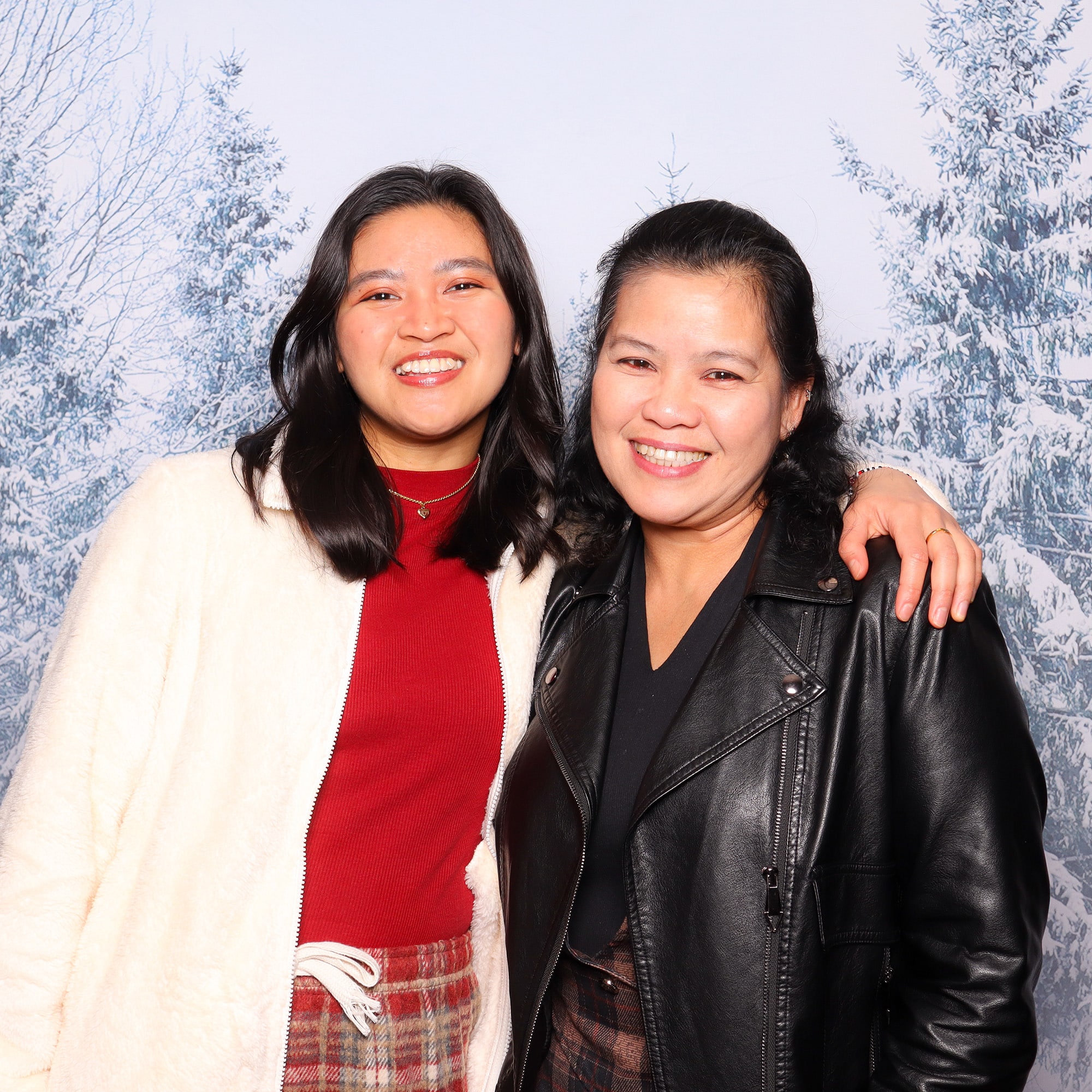 Smiling women posing for a holiday portrait against a snowy backdrop, showcasing a festive atmosphere and personalized photo experience.