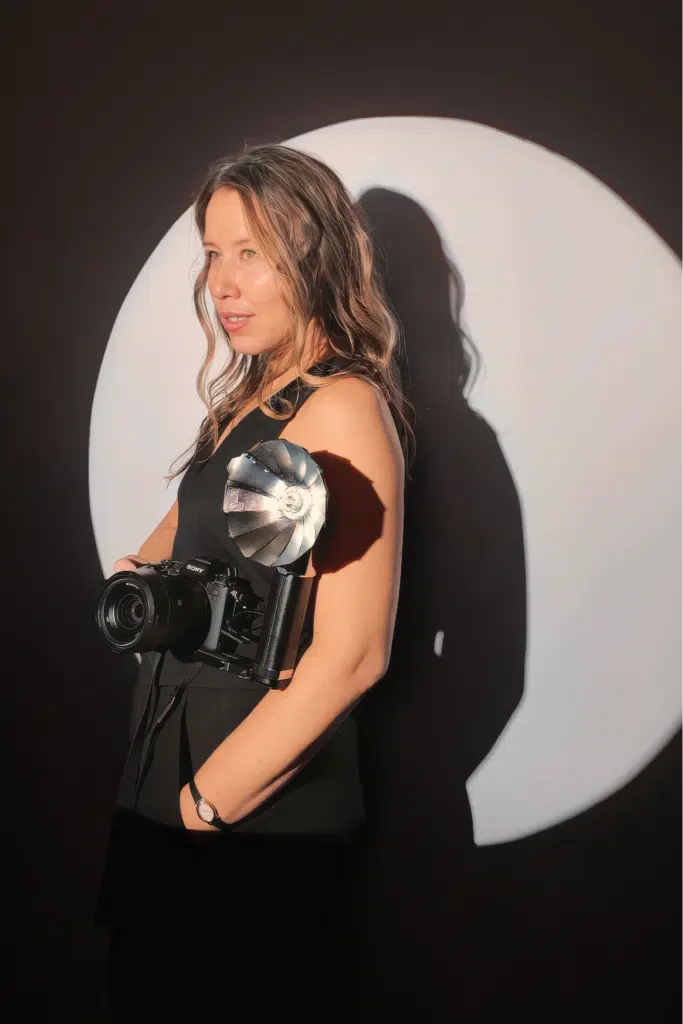 Woman holding a camera with dramatic lighting, showcasing the Spotlight Photo Booth service by Pop Life Photo for unique event photography experiences.
