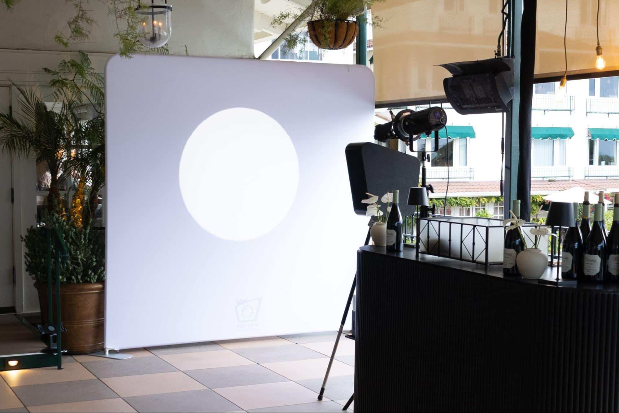 Spotlight Photo Booth setup featuring a sleek backdrop with dramatic lighting, designed for capturing high-end portraits at events, surrounded by stylish decor and a bar area.