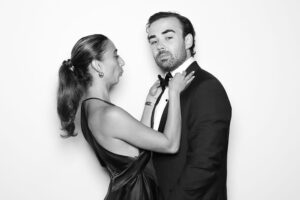 Couple in a playful pose inside a photo booth, showcasing intimacy and spontaneity, reflecting the fun and relaxed atmosphere of shared experiences at events like weddings and anniversaries.