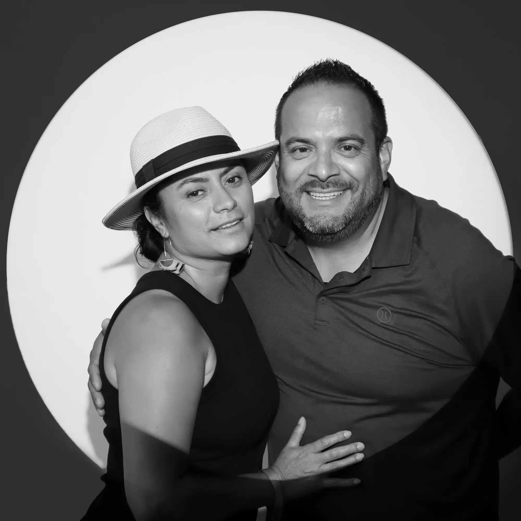 Couple posing for bold, editorial-style portrait in black-and-white, showcasing dramatic lighting against a circular backdrop, ideal for corporate event photography.