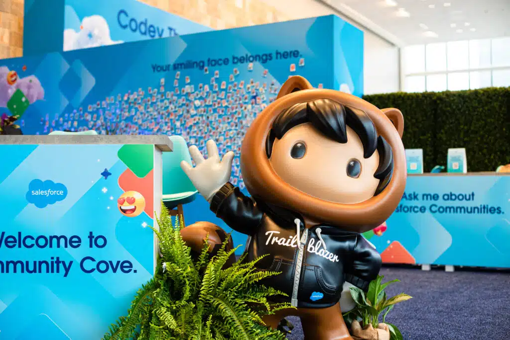 Salesforce Trailblazer mascot welcoming guests at Community Cove, surrounded by vibrant branding elements and greenery, representing engaging activations for corporate events.