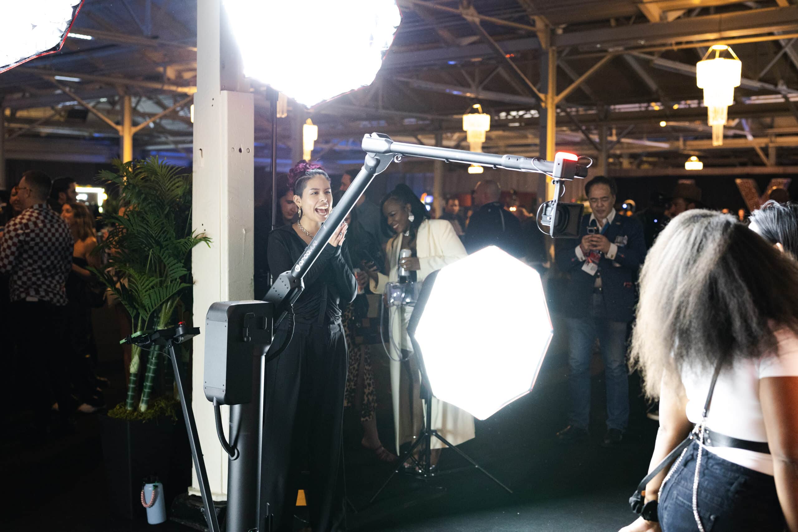 Event attendees interacting with a Glambot setup, featuring bright lighting and a photographer capturing moments at the Sports Illustrated Super Bowl Party.