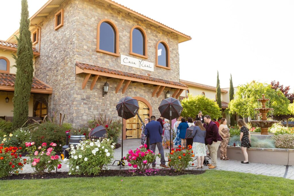 Guests celebrating WIPA SFBA's 10-Year Anniversary at Casa Real, surrounded by vibrant flowers and umbrellas, capturing moments in a festive outdoor setting.