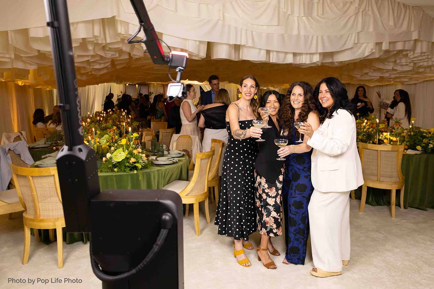 Group of four women celebrating at a stylish event with cocktails, elegant table settings, and a photo booth setup in a luxurious venue, capturing the essence of upscale parties in Walnut Creek, CA.