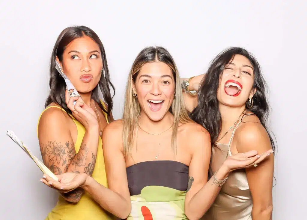 Three women posing playfully in a photo booth, showcasing fun expressions and stylish outfits, ideal for creative photo booth inspiration at Bay Area events.