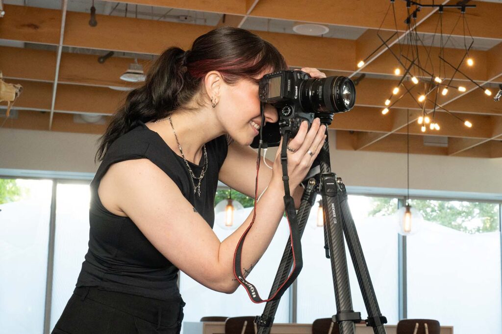 Professional photographer taking corporate headshots with a camera on a tripod in a modern indoor setting.