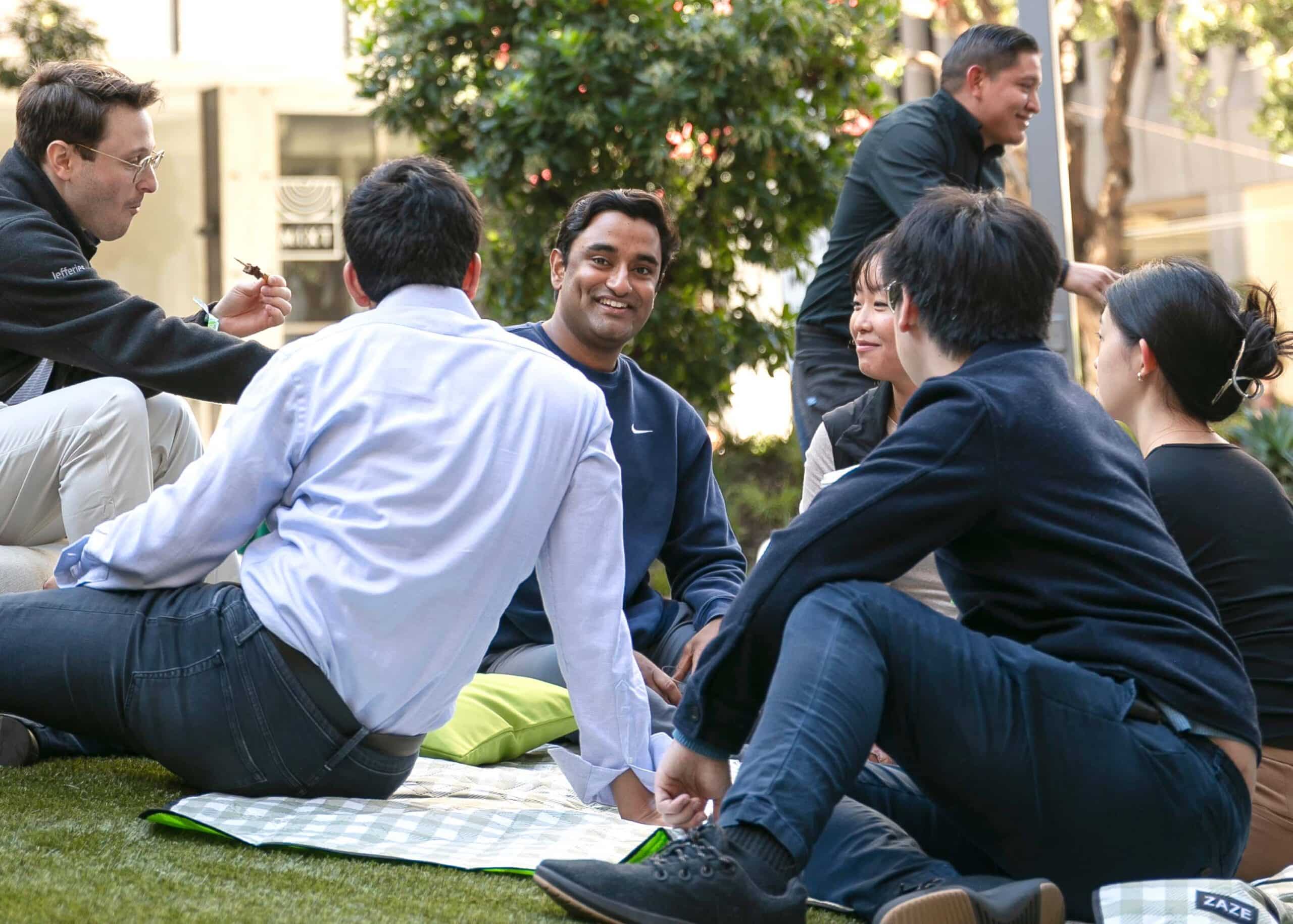 Group of friends enjoying a casual gathering outdoors in Palo Alto, sharing smiles and conversation on a picnic blanket, reflecting a vibrant event atmosphere.