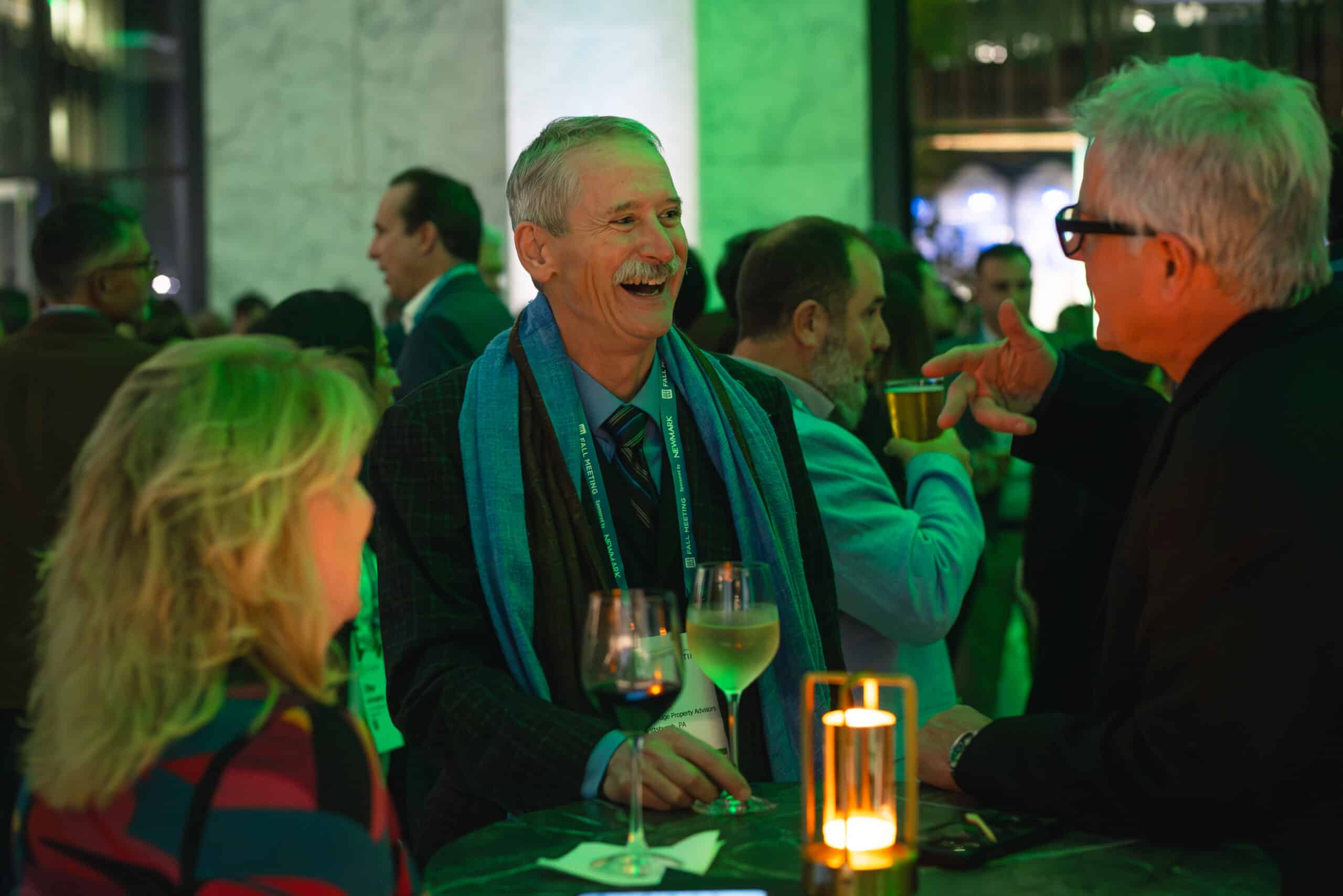 Group of event attendees engaging in conversation, smiling, and enjoying drinks at a festive gathering, with a focus on interaction and social sharing in a vibrant setting, reflecting Pop Life Photo's event photography services.