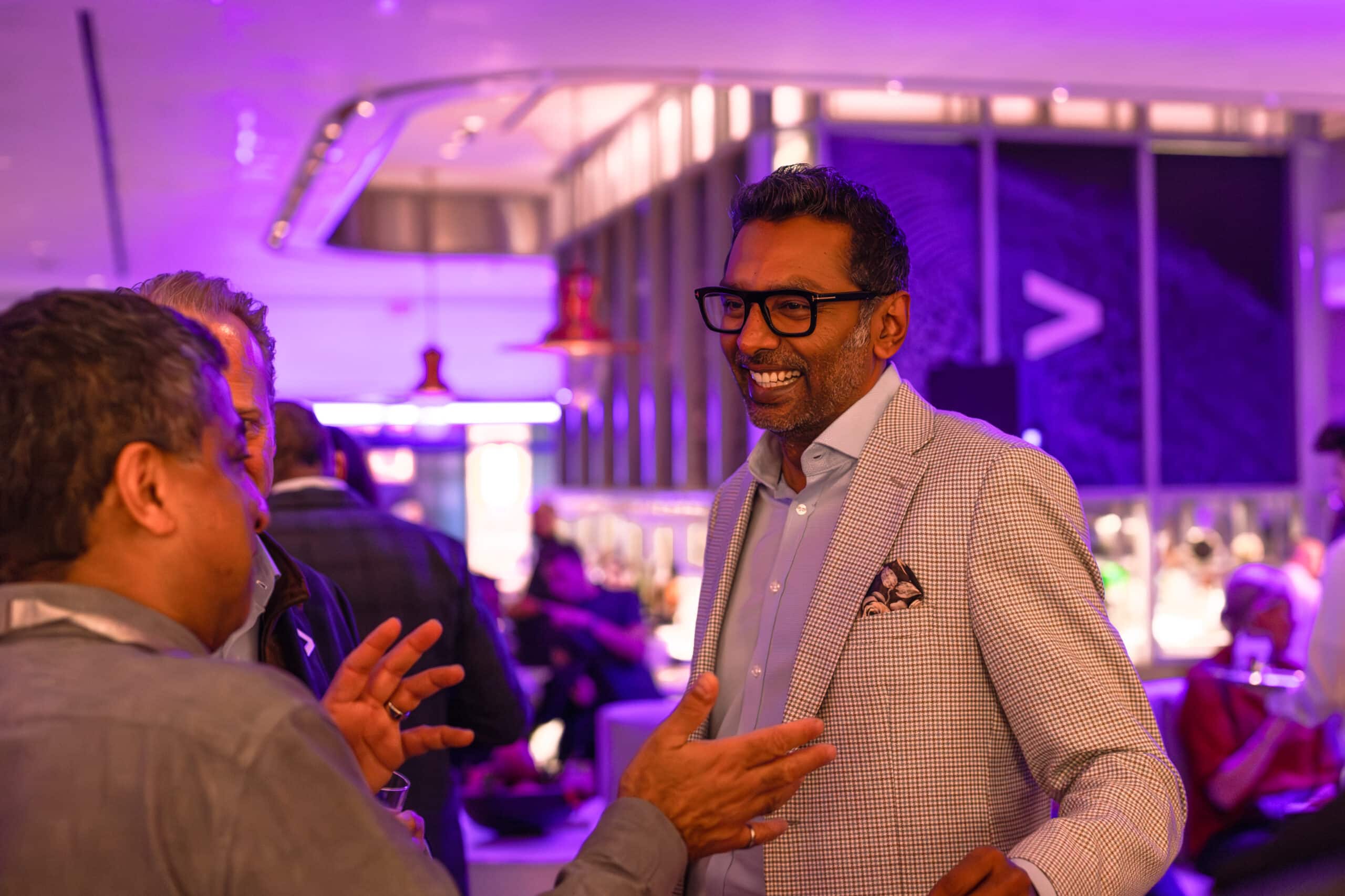 Smiling man in a stylish blazer engaging in conversation at a vibrant corporate event, showcasing real-time guest interaction and engagement.
