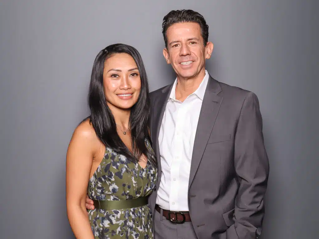 a couple posing in front of a clean glam booth photo booth with a dark grey backdrop