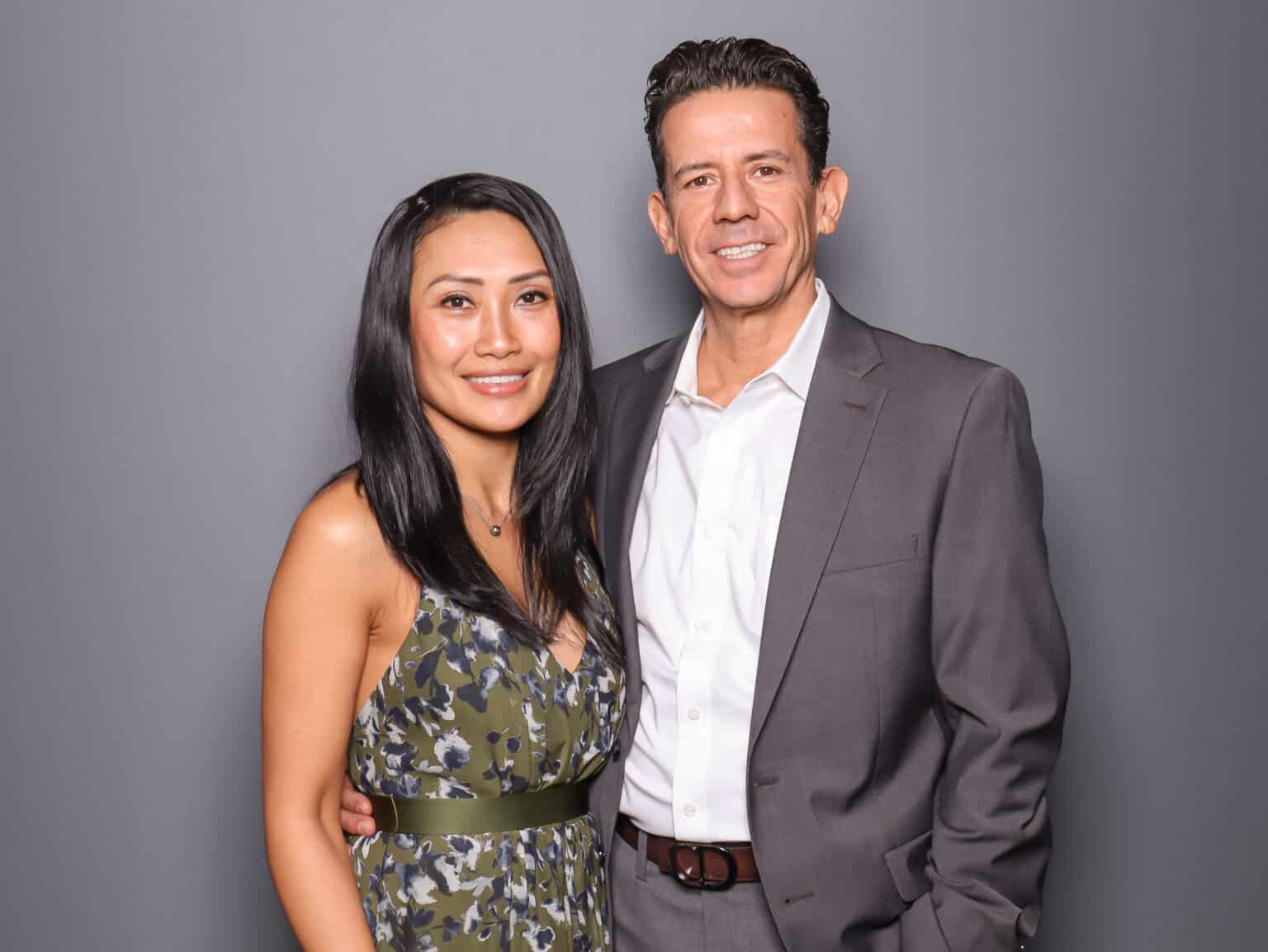 Couple posing for photo booth portrait with a cool gray backdrop.