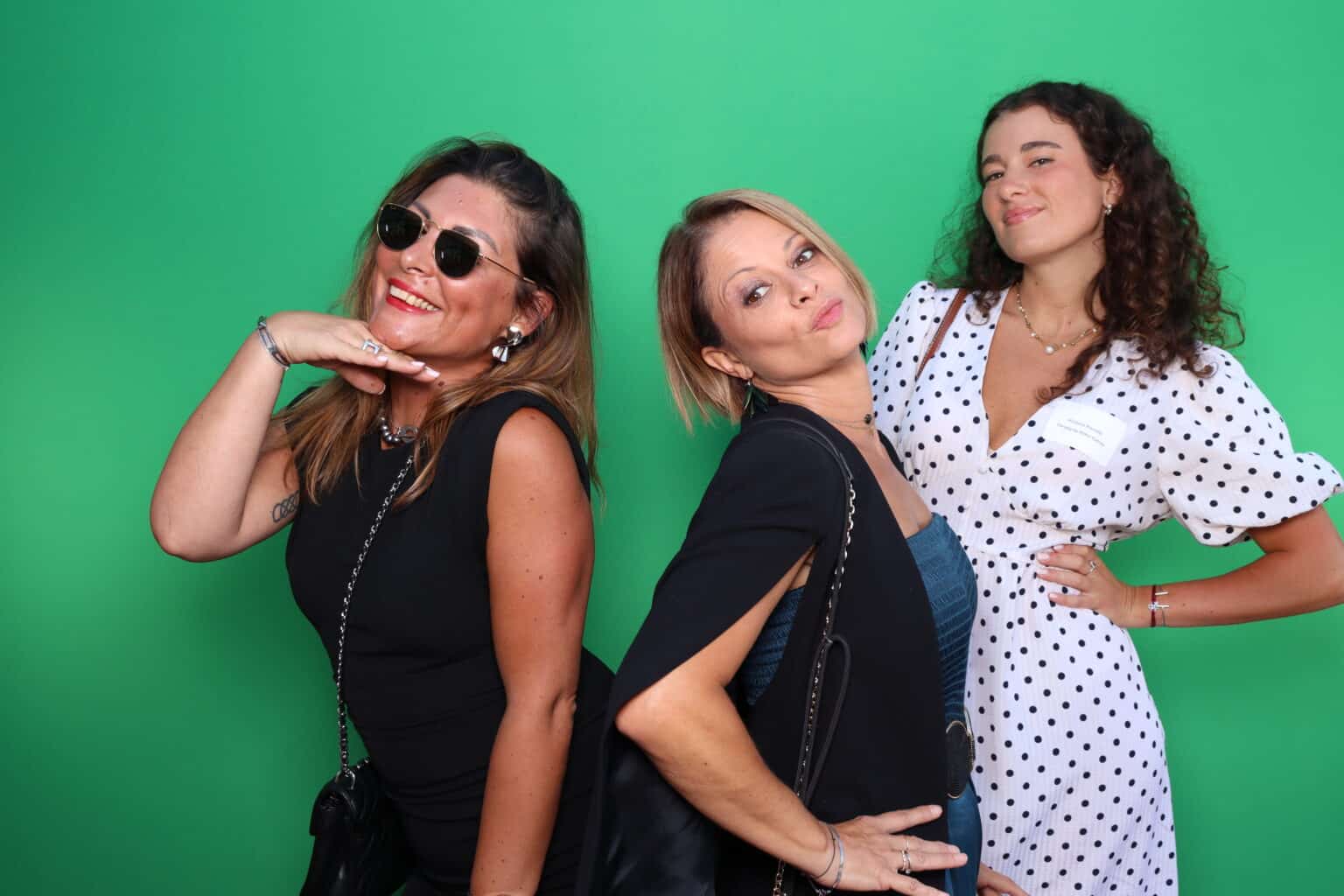 Emerald green tension fabric backdrop with smiling women posing for a photo booth experience.