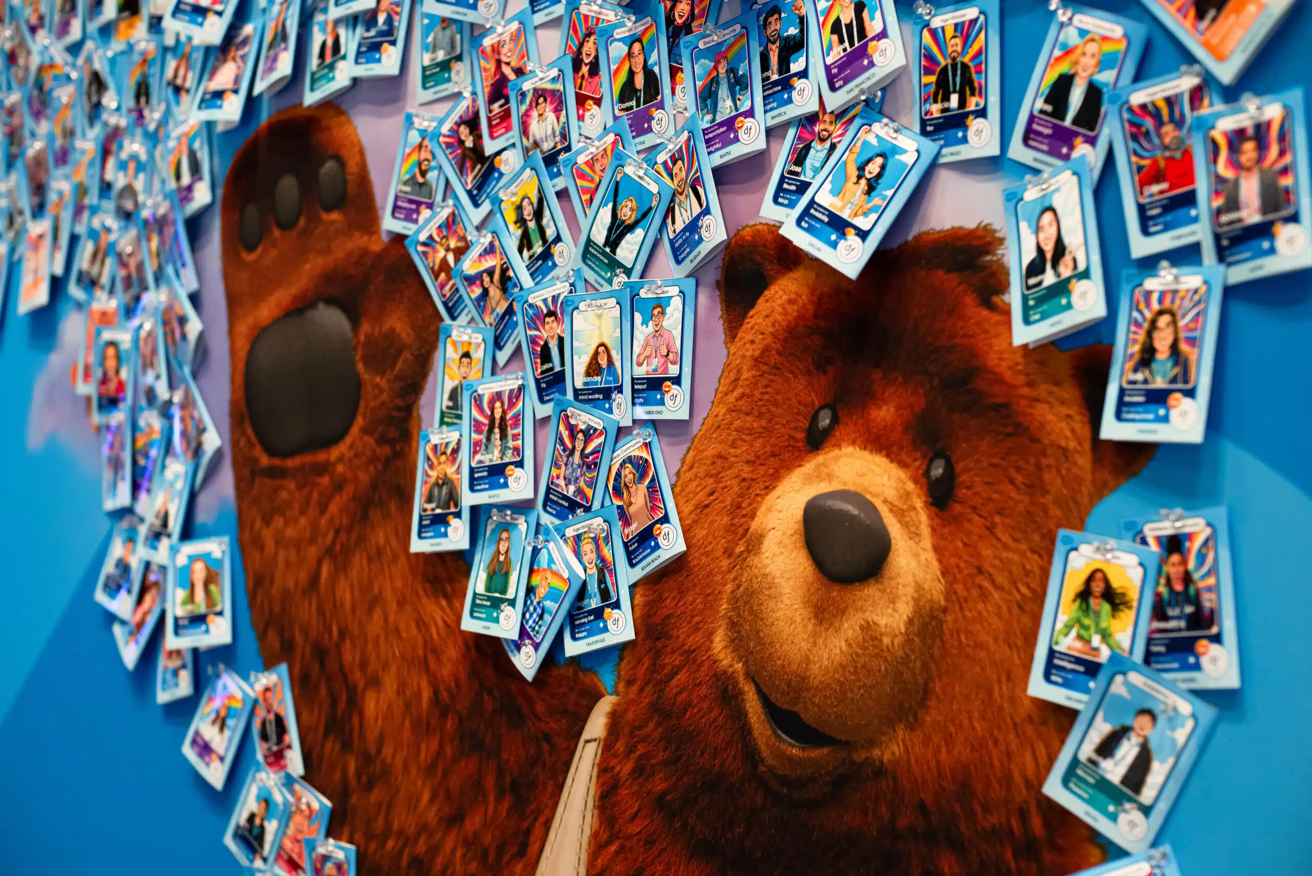 AI-powered trading card activation featuring a bear mascot with colorful trading cards displayed on a blue backdrop, highlighting participant engagement from the Dreamforce 2025 event.