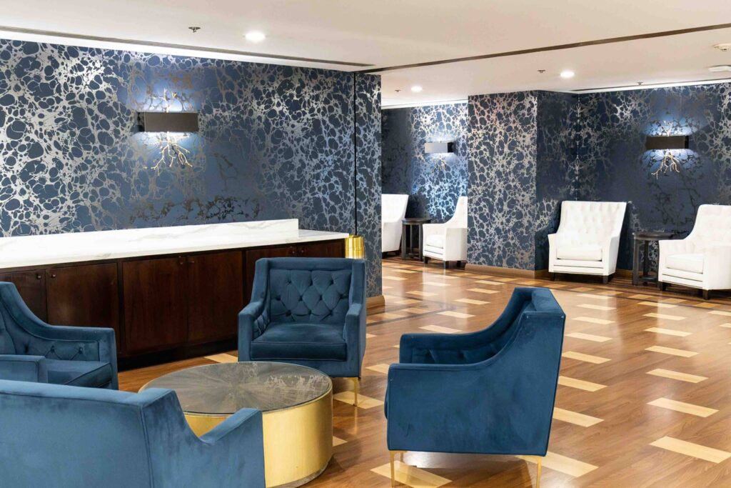 Elegant lounge area at Hotel Nikko San Francisco featuring blue velvet chairs, a marble counter, and stylish decor, ideal for luxury events and gatherings.