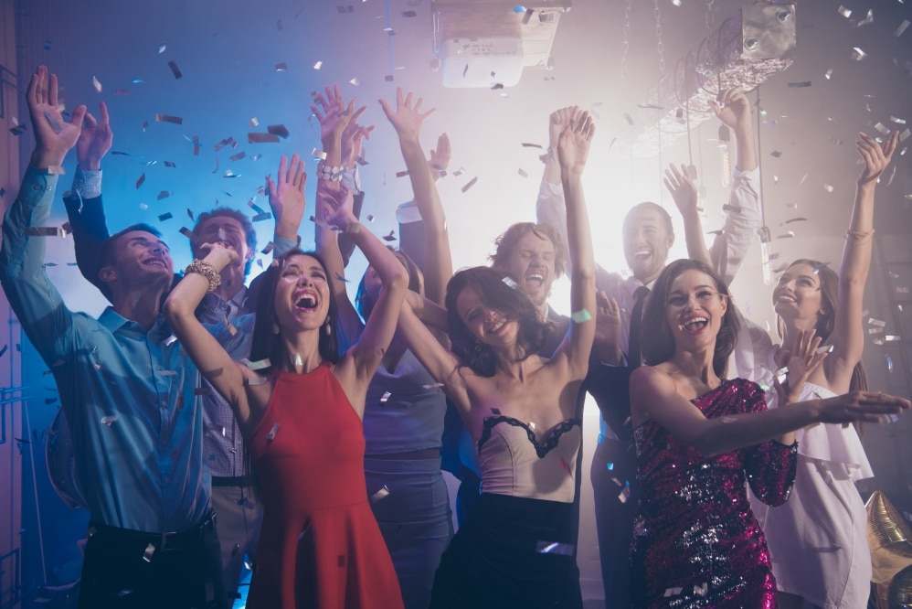Group of joyful people celebrating at a corporate event with confetti, showcasing engagement and excitement, reflecting innovative event planning.