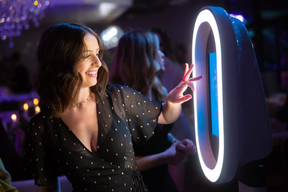 Woman interacting with a modern photo booth at a corporate event, showcasing Pop Life Photo Booth's services.