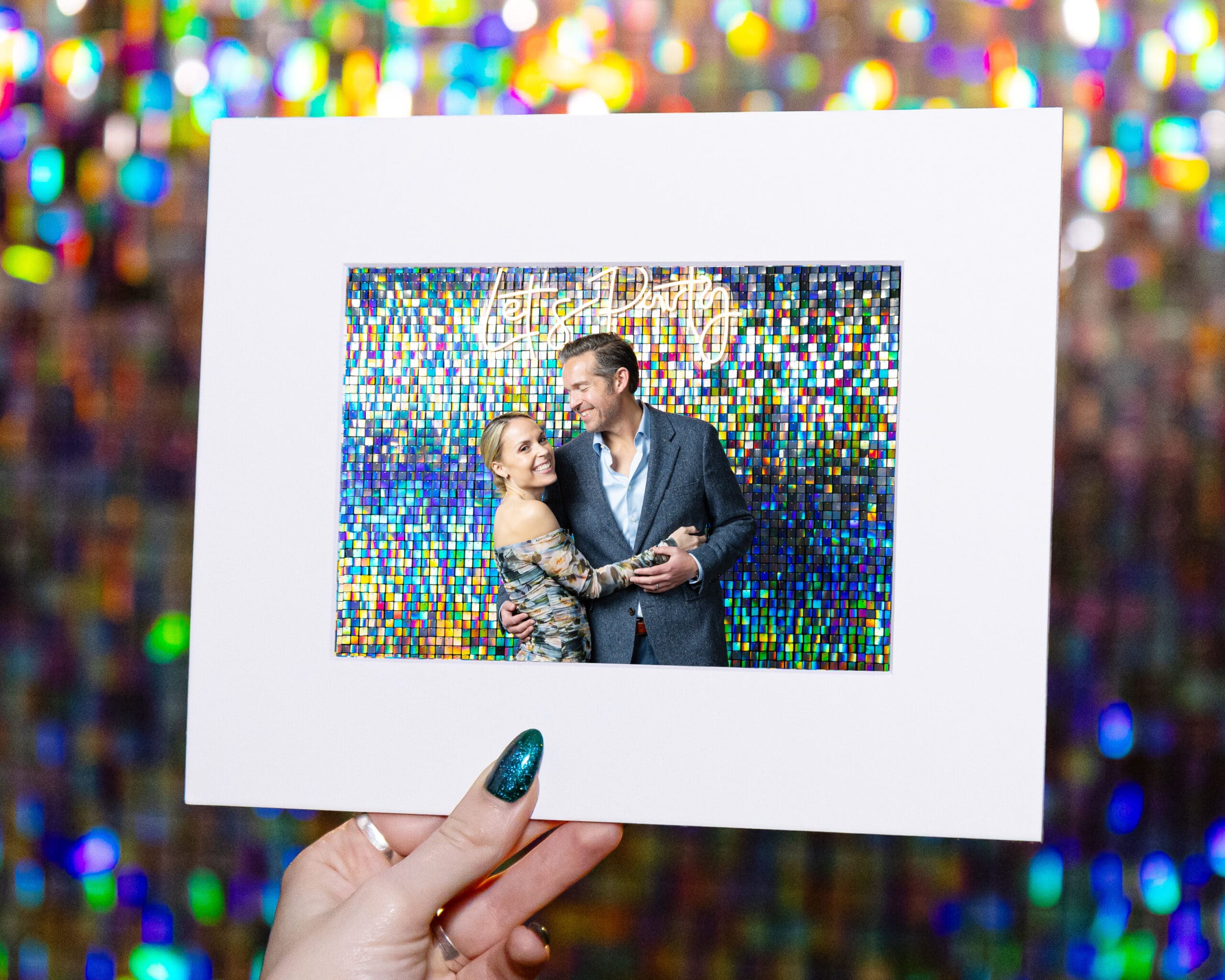Couple posing for a portrait in front of a colorful sequin backdrop, holding a framed photo, highlighting the upscale, personalized experience of Pop Life Photo's portrait studio services.