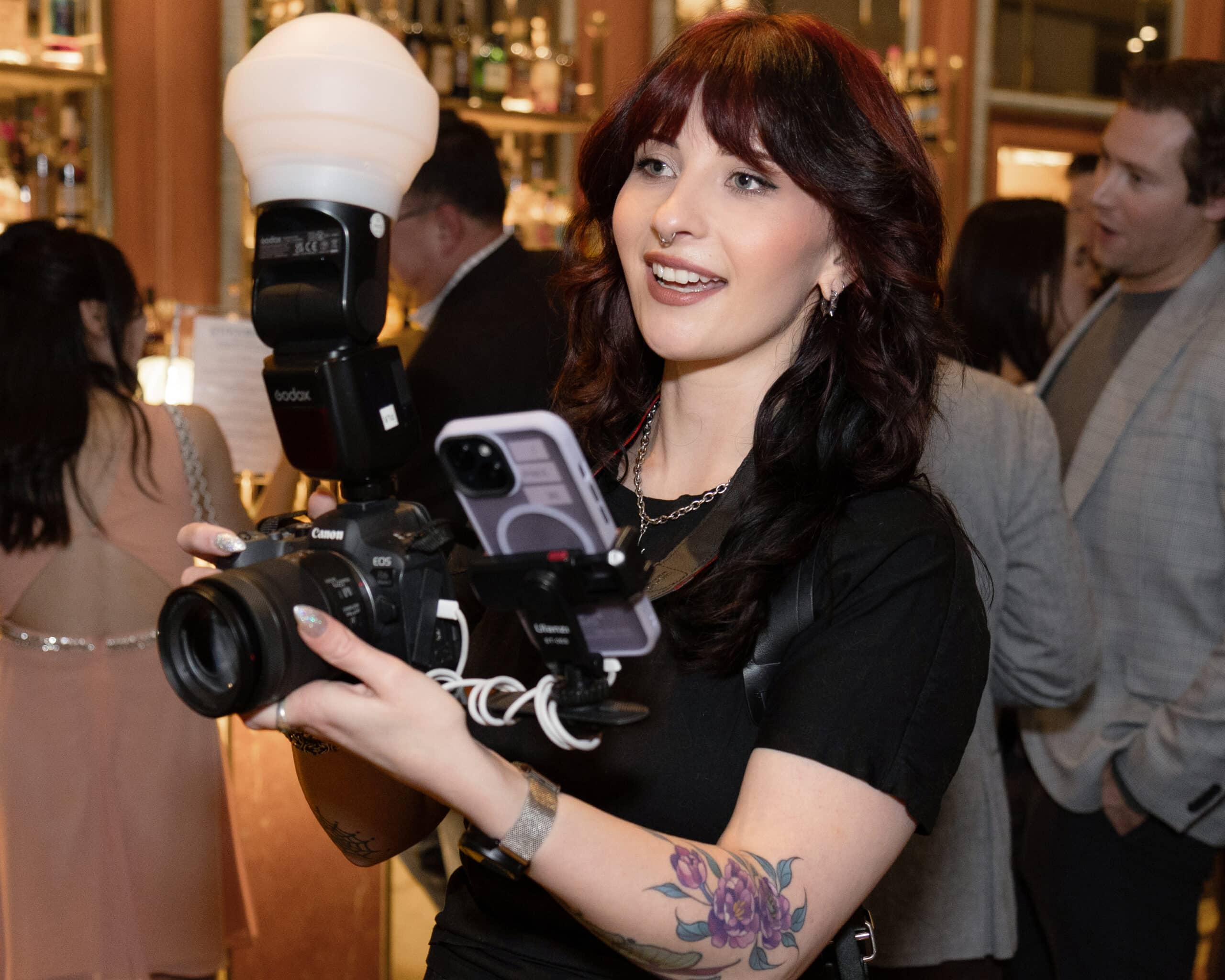 Professional photographer capturing moments at an event, holding a camera with flash, showcasing engagement and brand visibility.