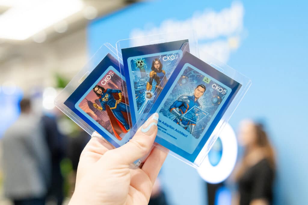 Hand holding three AI trading cards featuring superhero characters, designed for corporate branding and engagement at events, with a blue background highlighting experiential marketing.