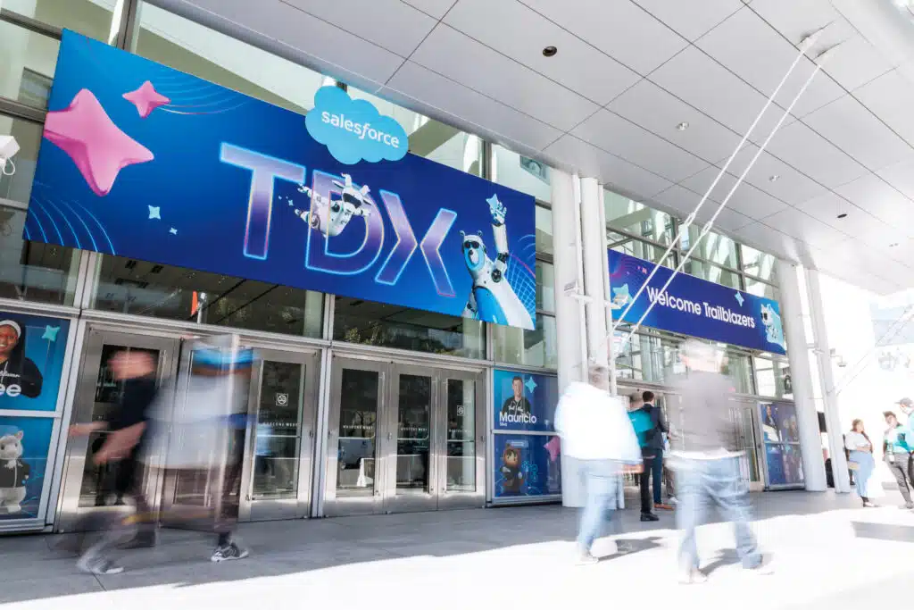 Salesforce TDX event entrance with vibrant signage, featuring "Welcome Trailblazers" and animated character graphics, bustling with attendees arriving for the conference in San Francisco.