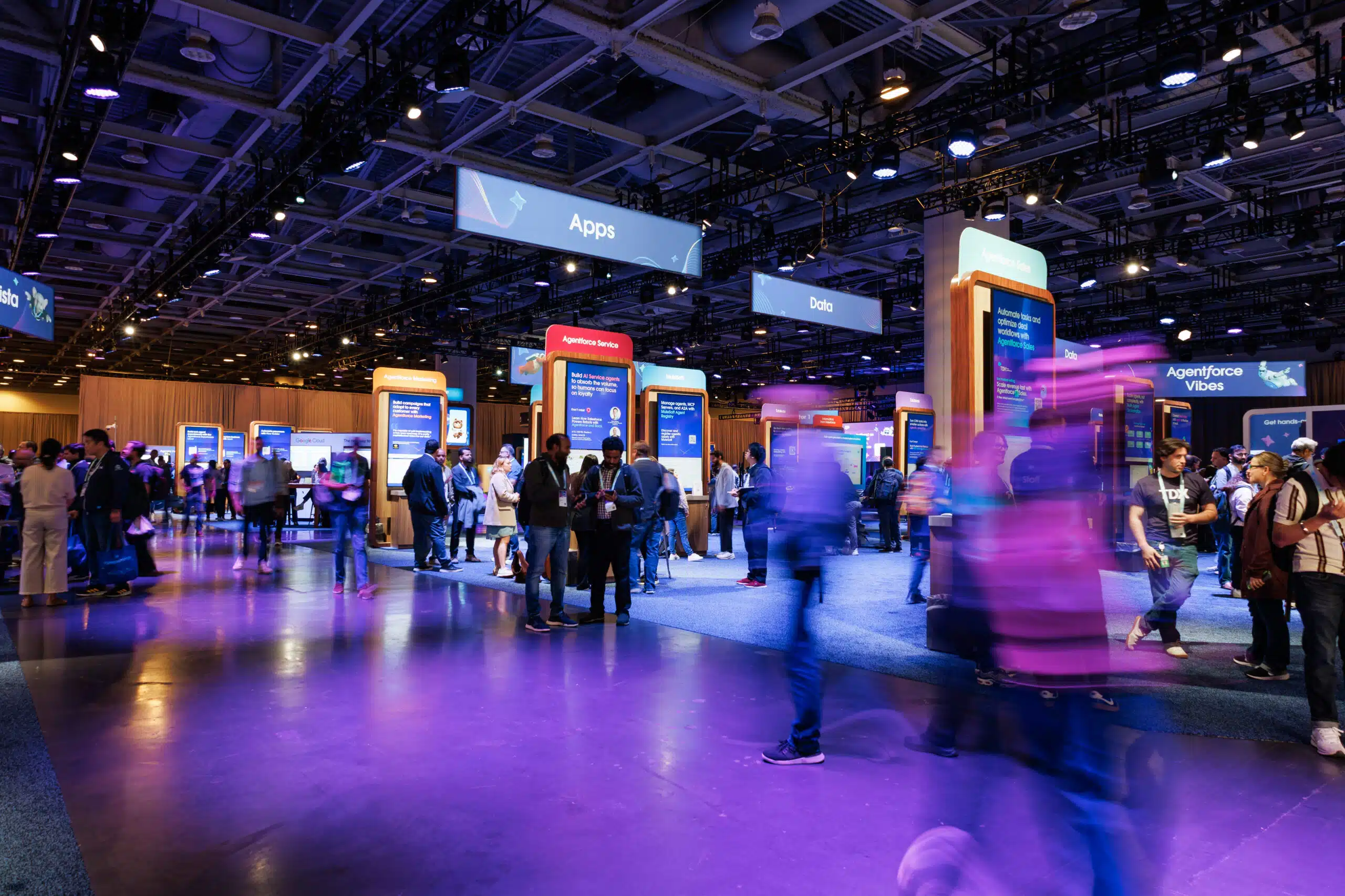 Crowd of attendees engaging at Salesforce TDX 2026 conference, with interactive booths labeled "Apps" and "Data" showcasing digital experiences.