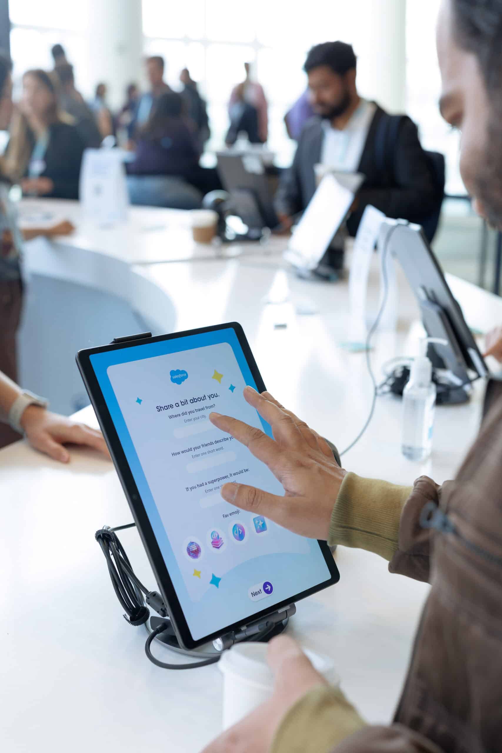 Person interacting with a tablet displaying an interactive survey at Salesforce TDX 2026 event, showcasing engagement in the AI Trading Card activation by Pop Life Photo.