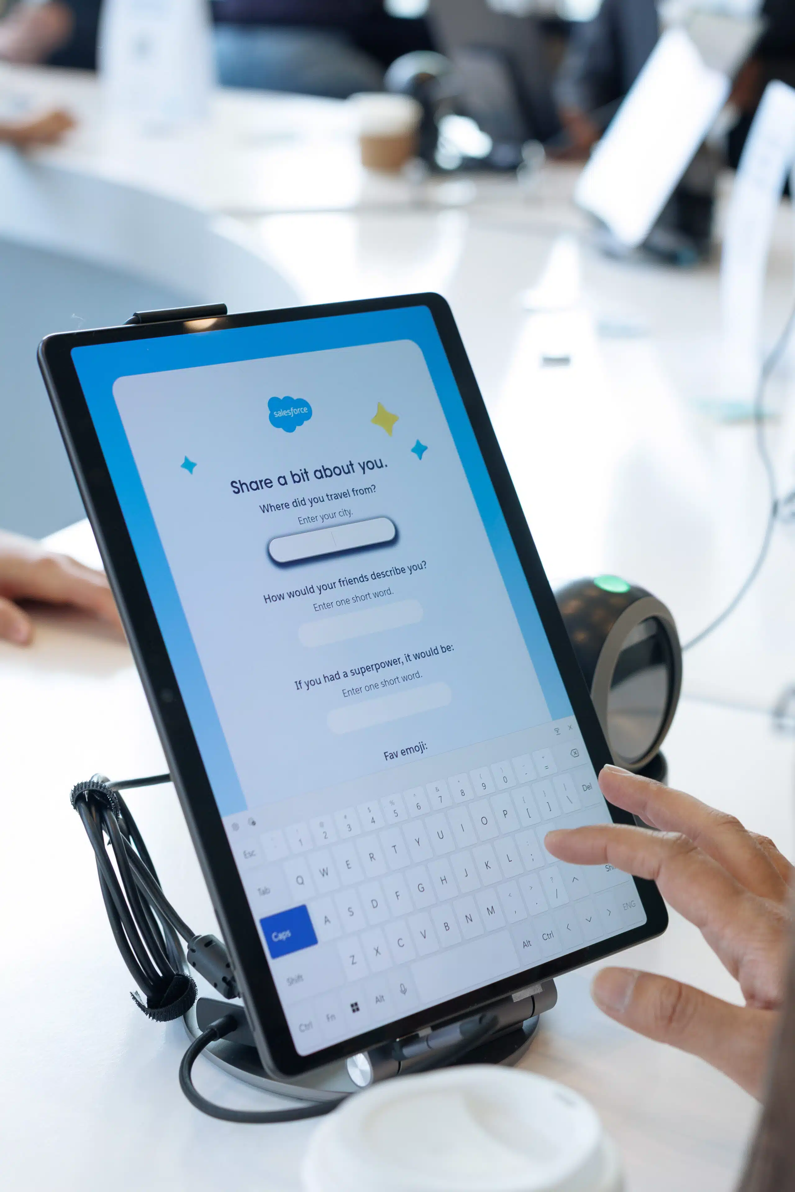 Hand interacting with a tablet displaying a personalized engagement questionnaire for event attendees, featuring prompts for travel origins and personal descriptors, aligned with the theme of experiential marketing and personalization in corporate events.