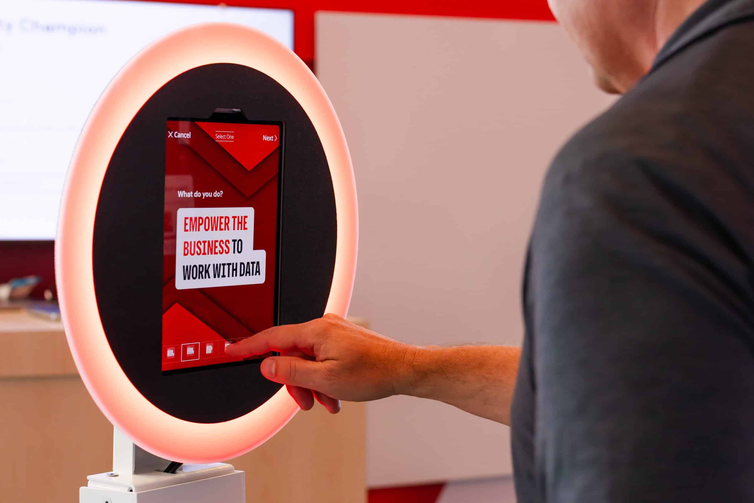 Branded corporate photo booth with ring light and touchscreen interface, showing "Empower the business to work with data" display.