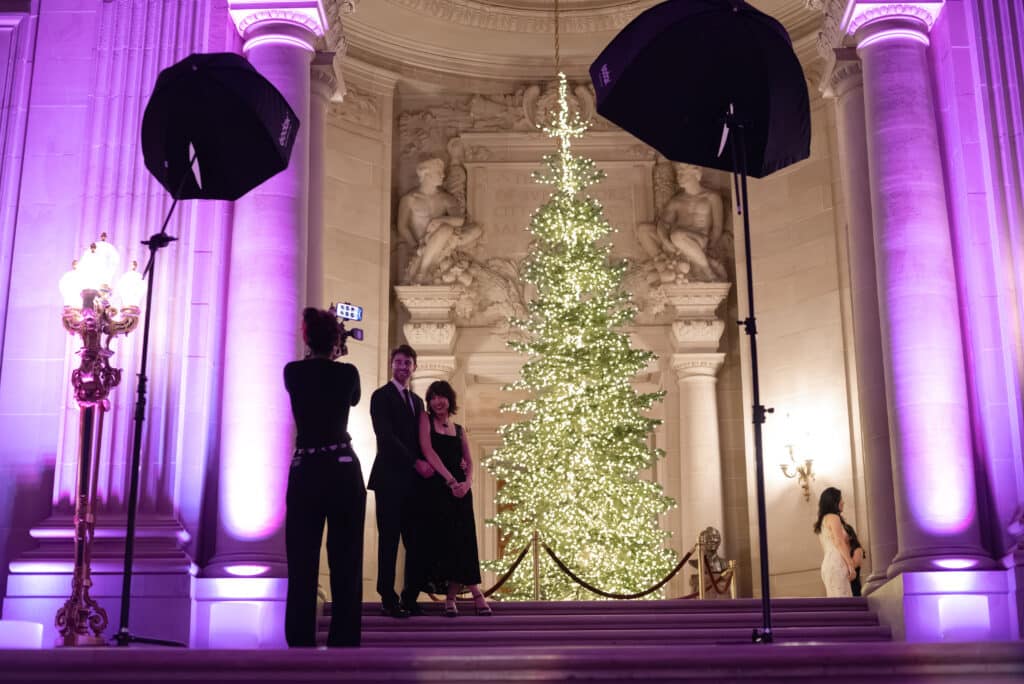 Pop Life Photo team capturing portraits at McKinsey holiday event, illuminated Christmas tree backdrop.